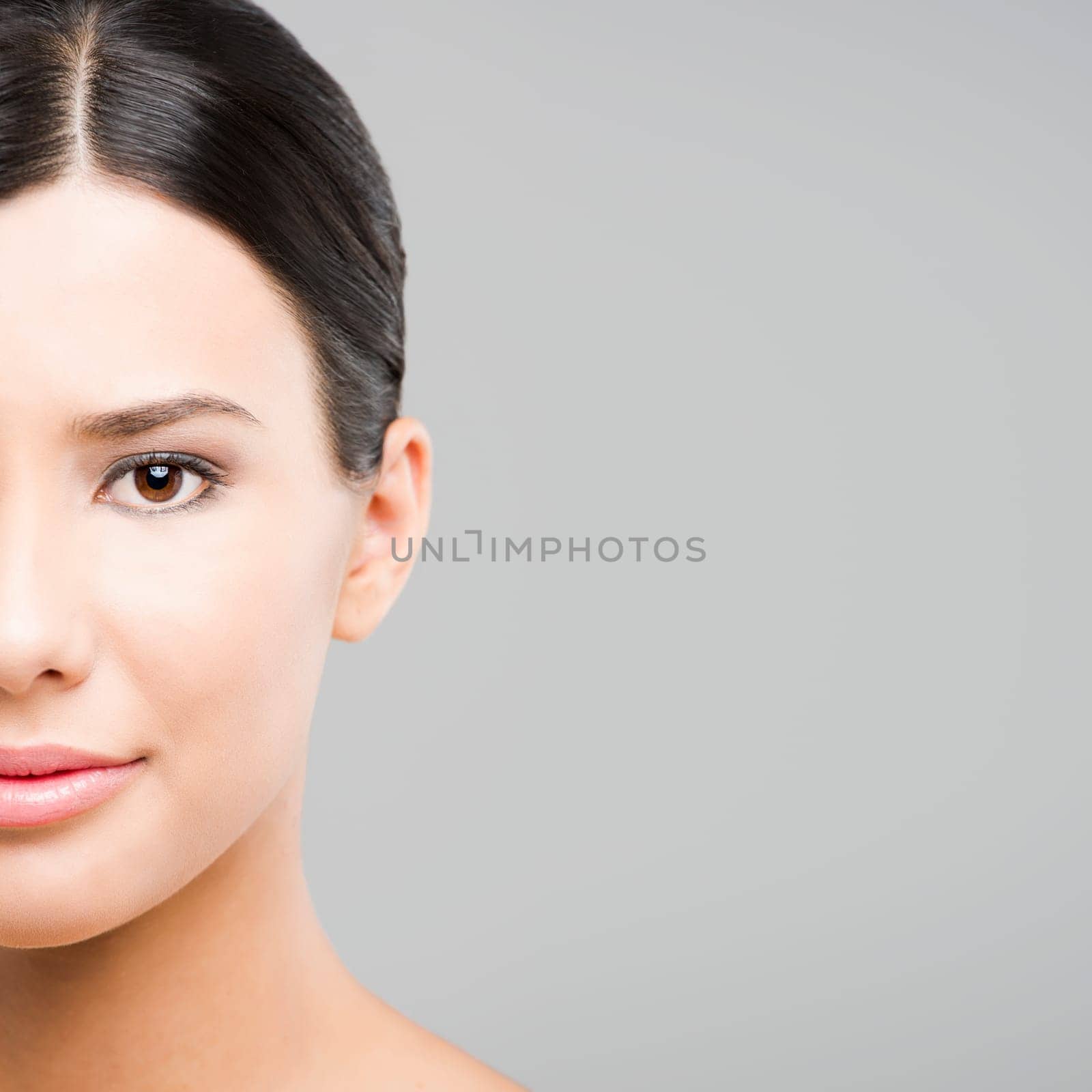 Beauty portrait of young asian woman smiling, over a gray background.