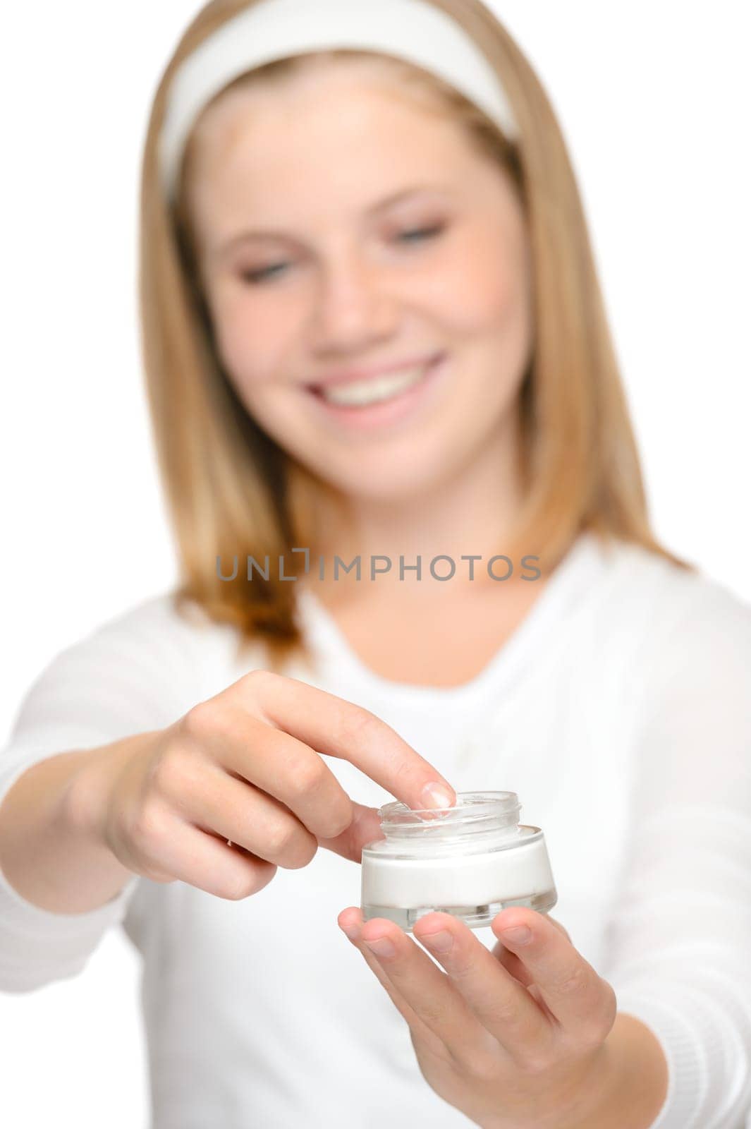 Smiling young girl applying moisturizer cream face beauty