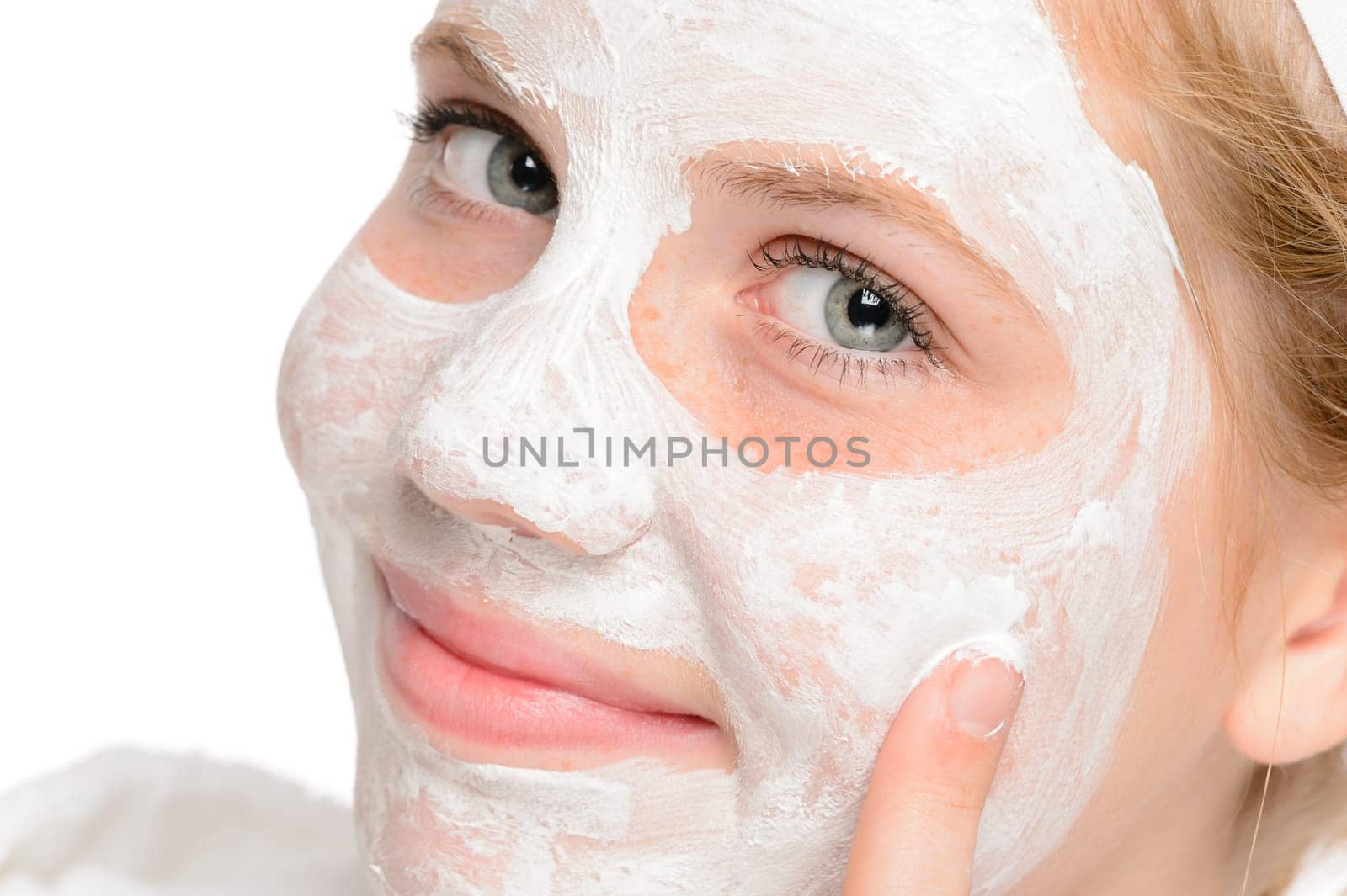 Young smiling girl applying cleaning facial mask treatment beauty