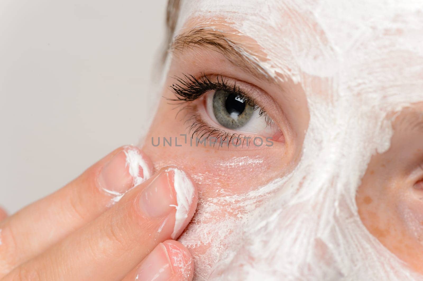 Young girl fingers applying face mask moisturizer cleaning skin