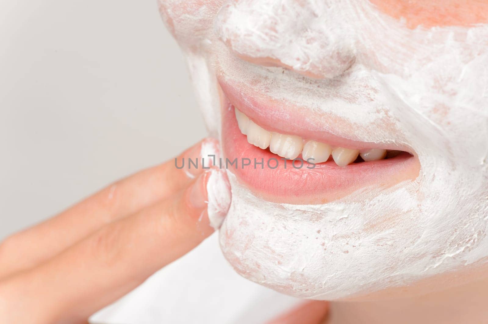 Smiling girl putting facial mask fingers cleaning treatment beauty