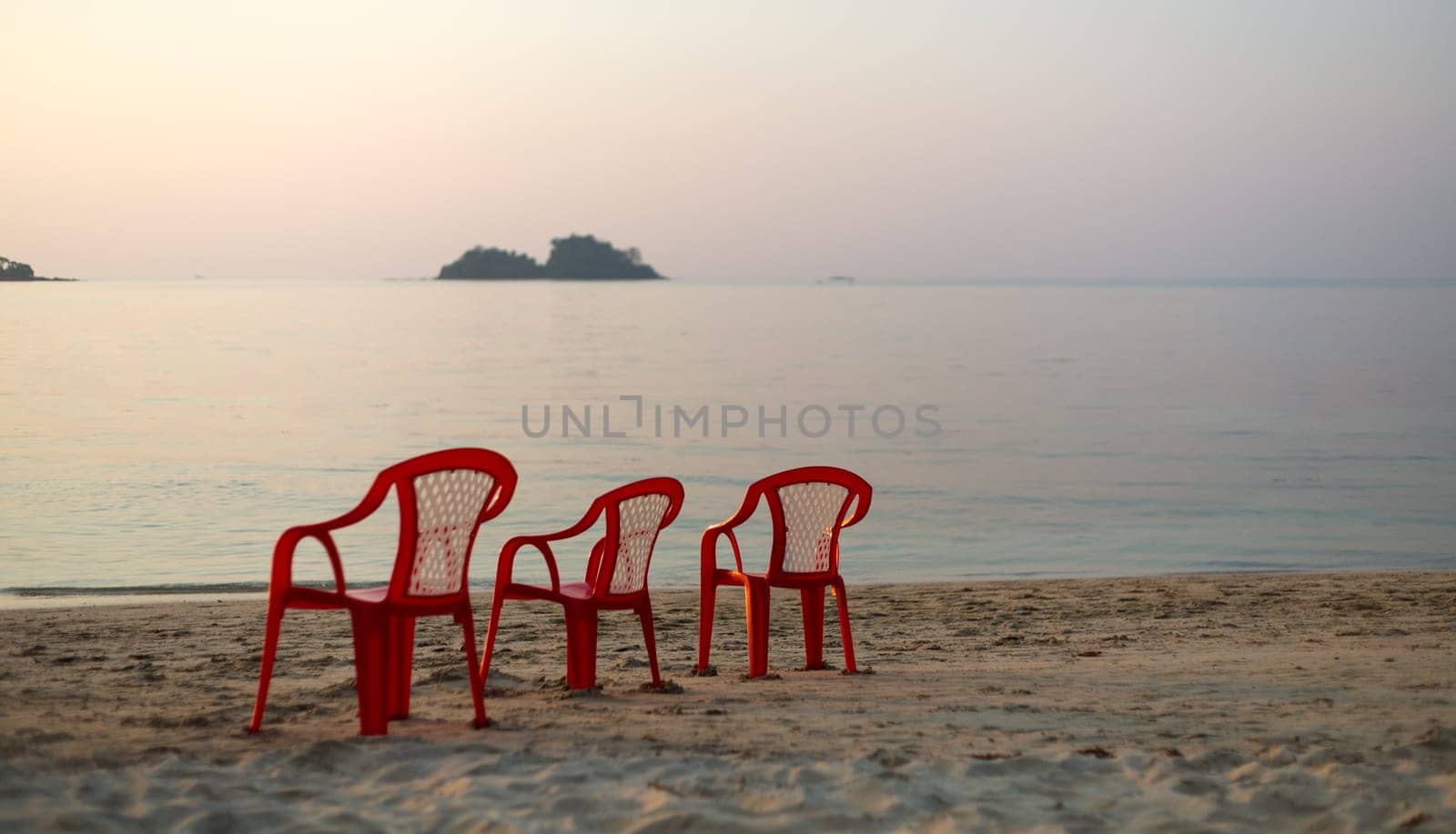 three red chair on an empty beach. sunset
