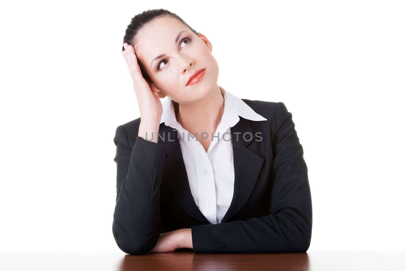 Pretty business woman in sitting at the desk and thinking, isolated on white