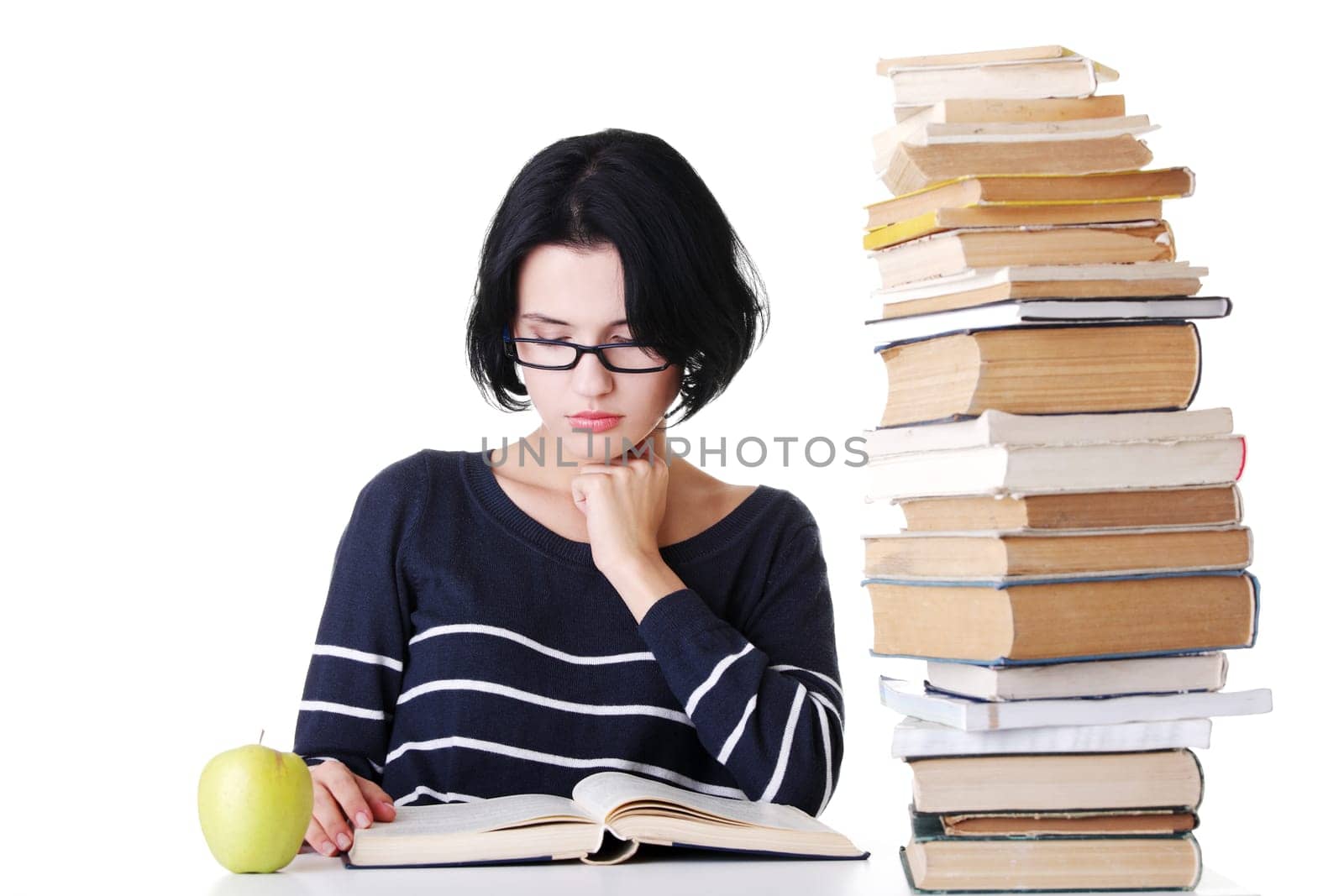 Young student woman with books studying at the desk, isolated on white background
