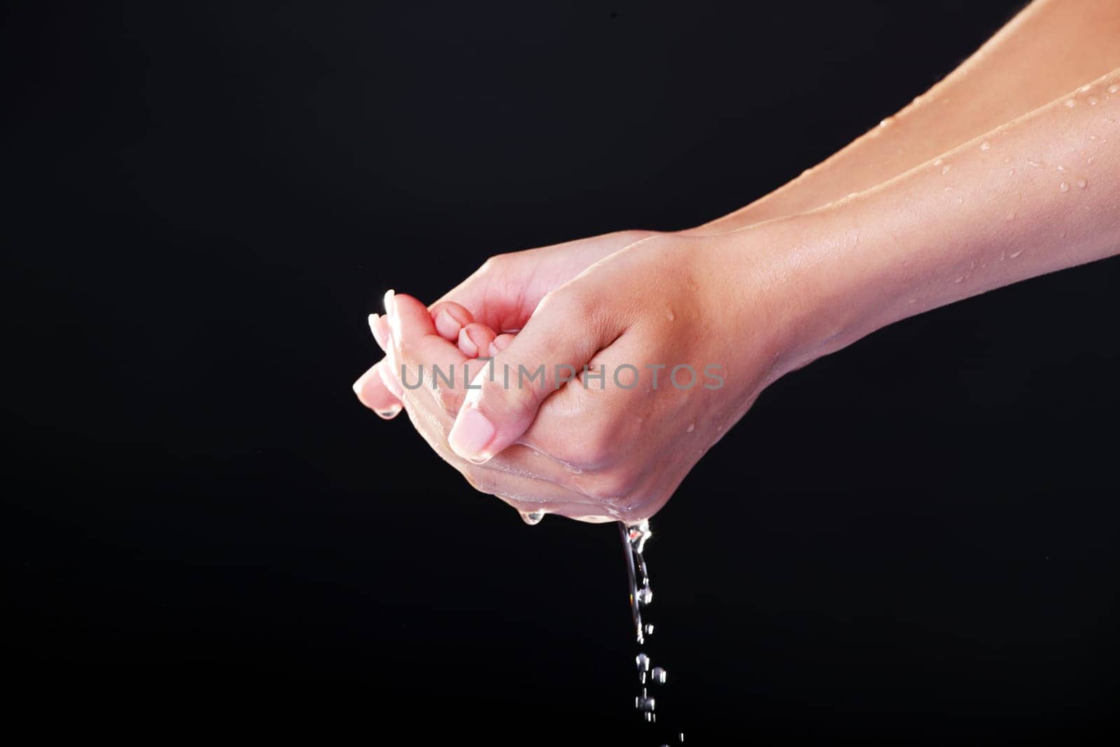 Water falling on female hands, over black background
