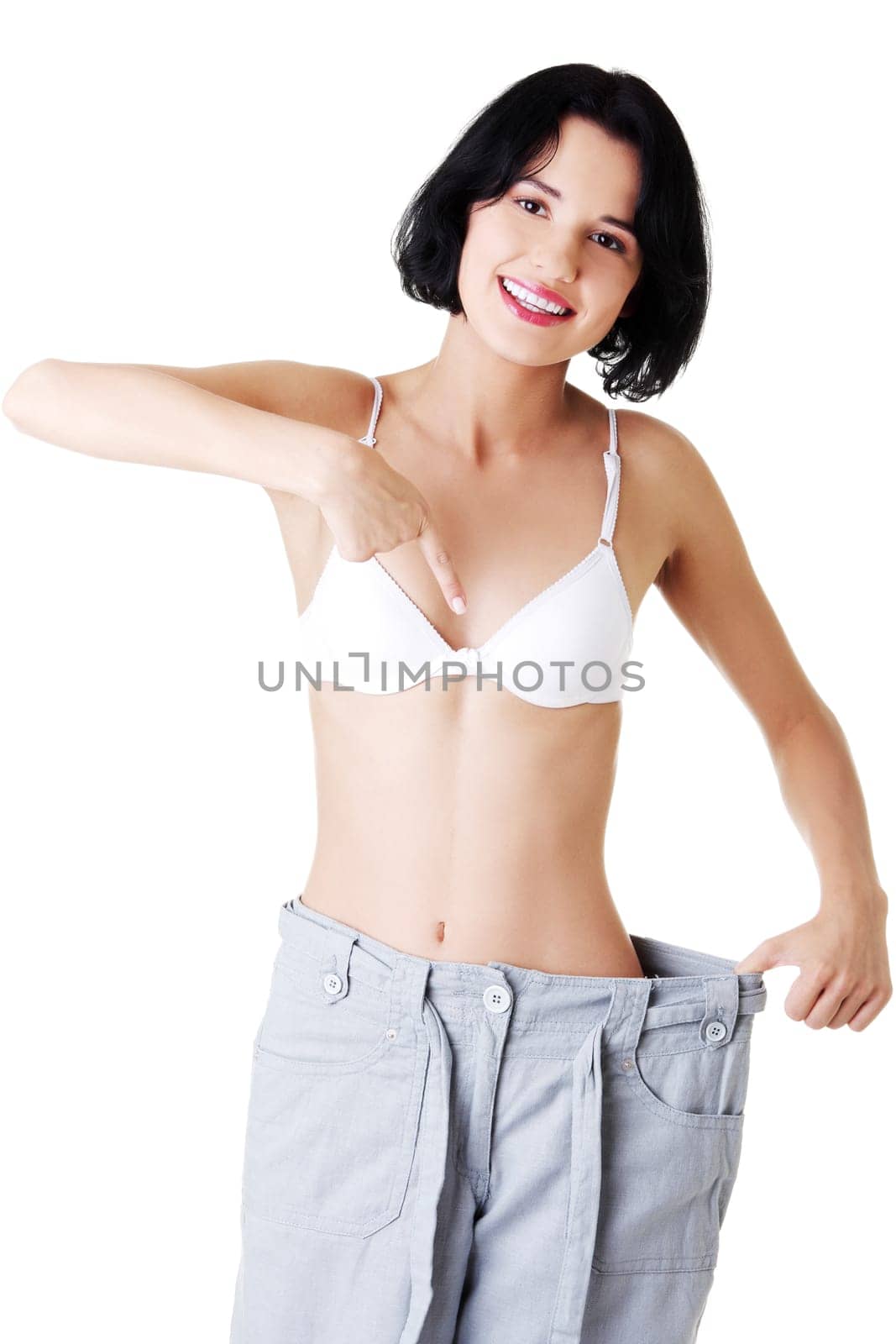 Young fit woman showing how much weight did she lost. Isolated on white