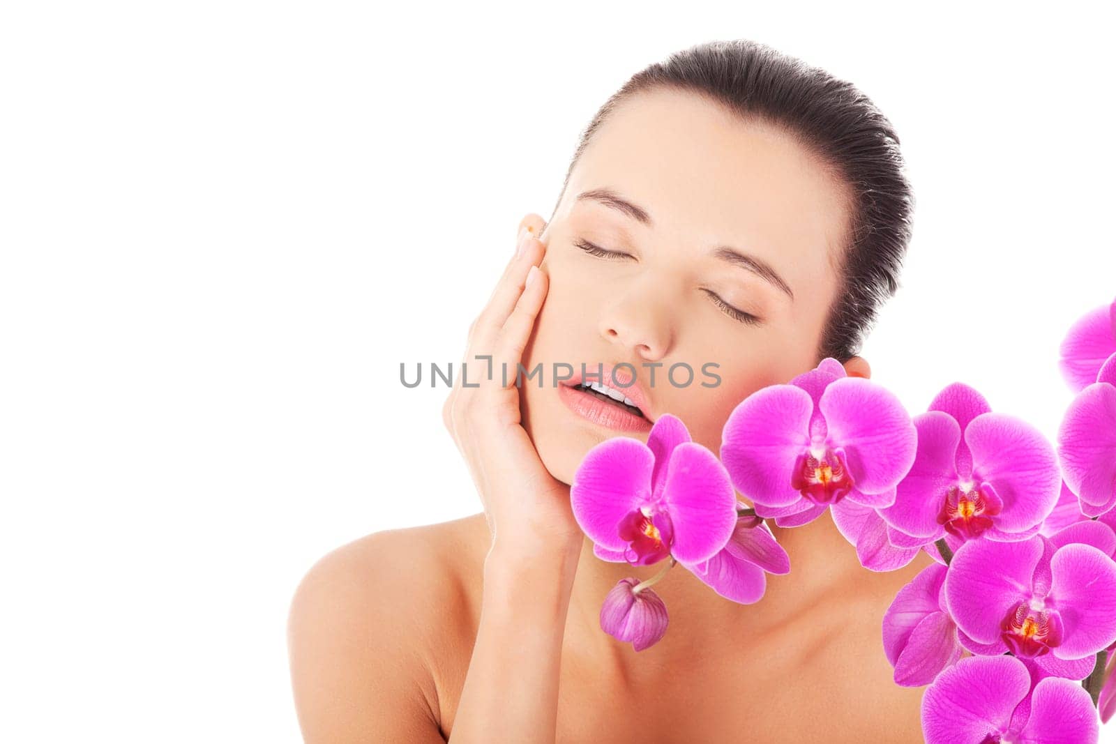 Portrait of beautiful young woman with health skin and with orchid flower. Spa concept.
