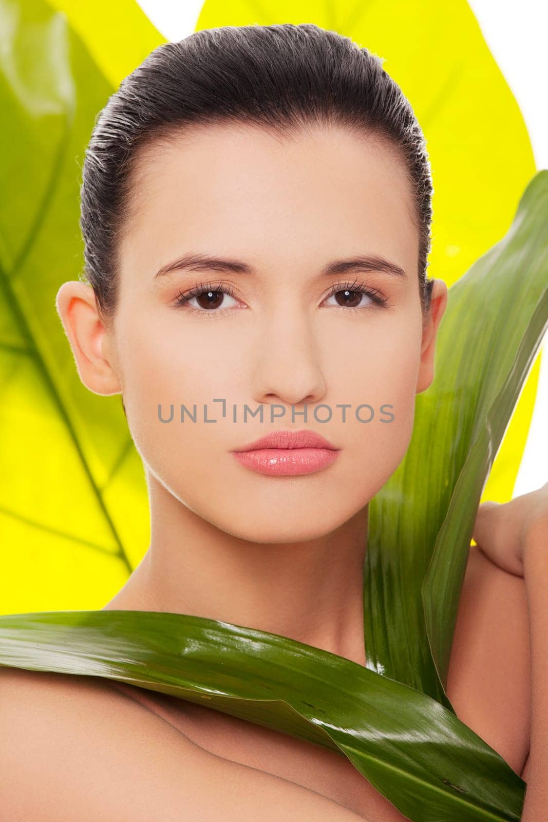 Portrait of young beautiful woman at spa with green leafs in background