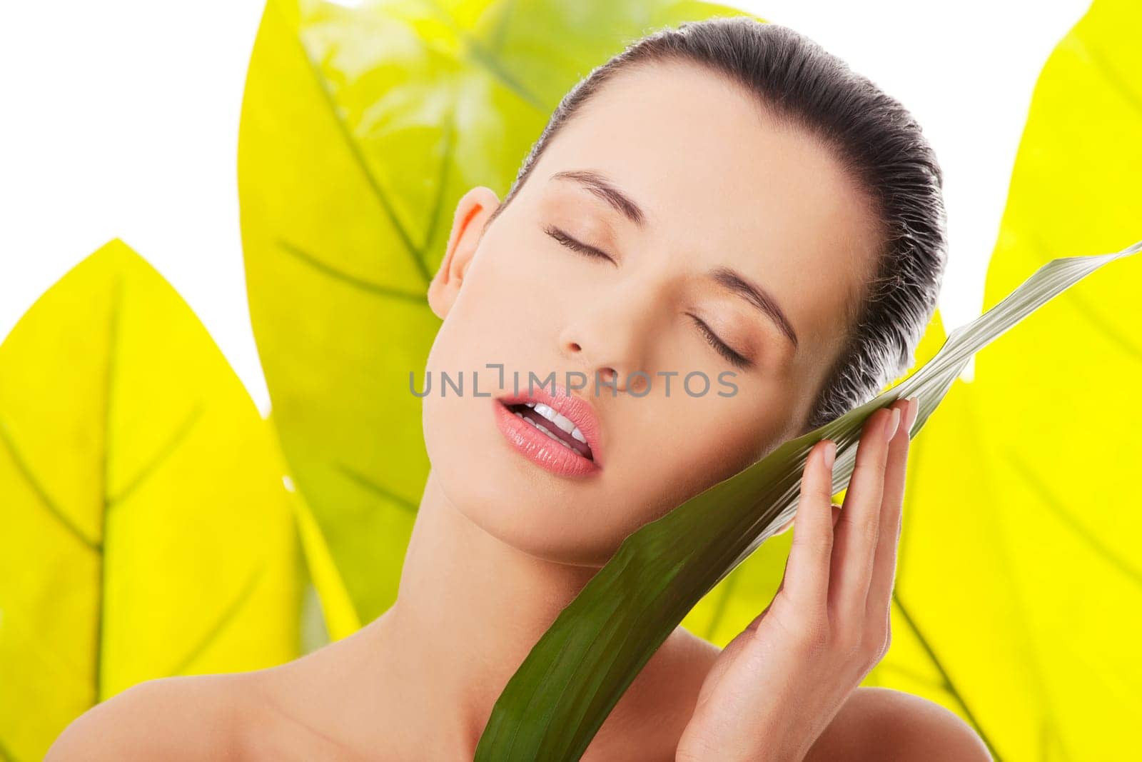 Portrait of young beautiful woman at spa with green leafs in background
