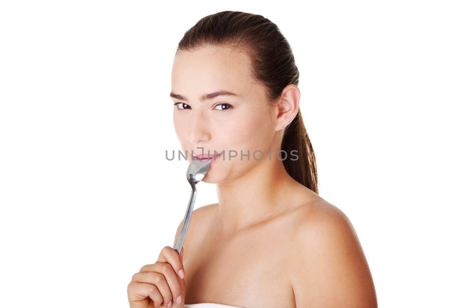 Teen girl with spoon in mouth. Isolated on white