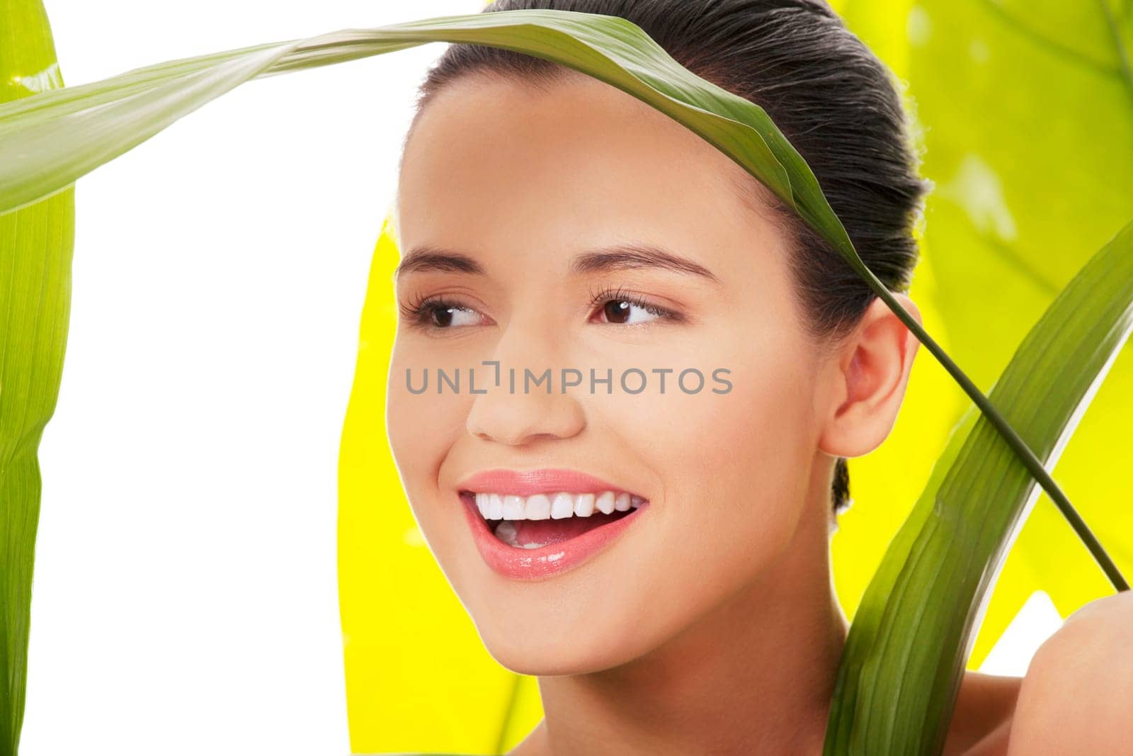 Portrait of young beautiful woman at spa with green leafs in background