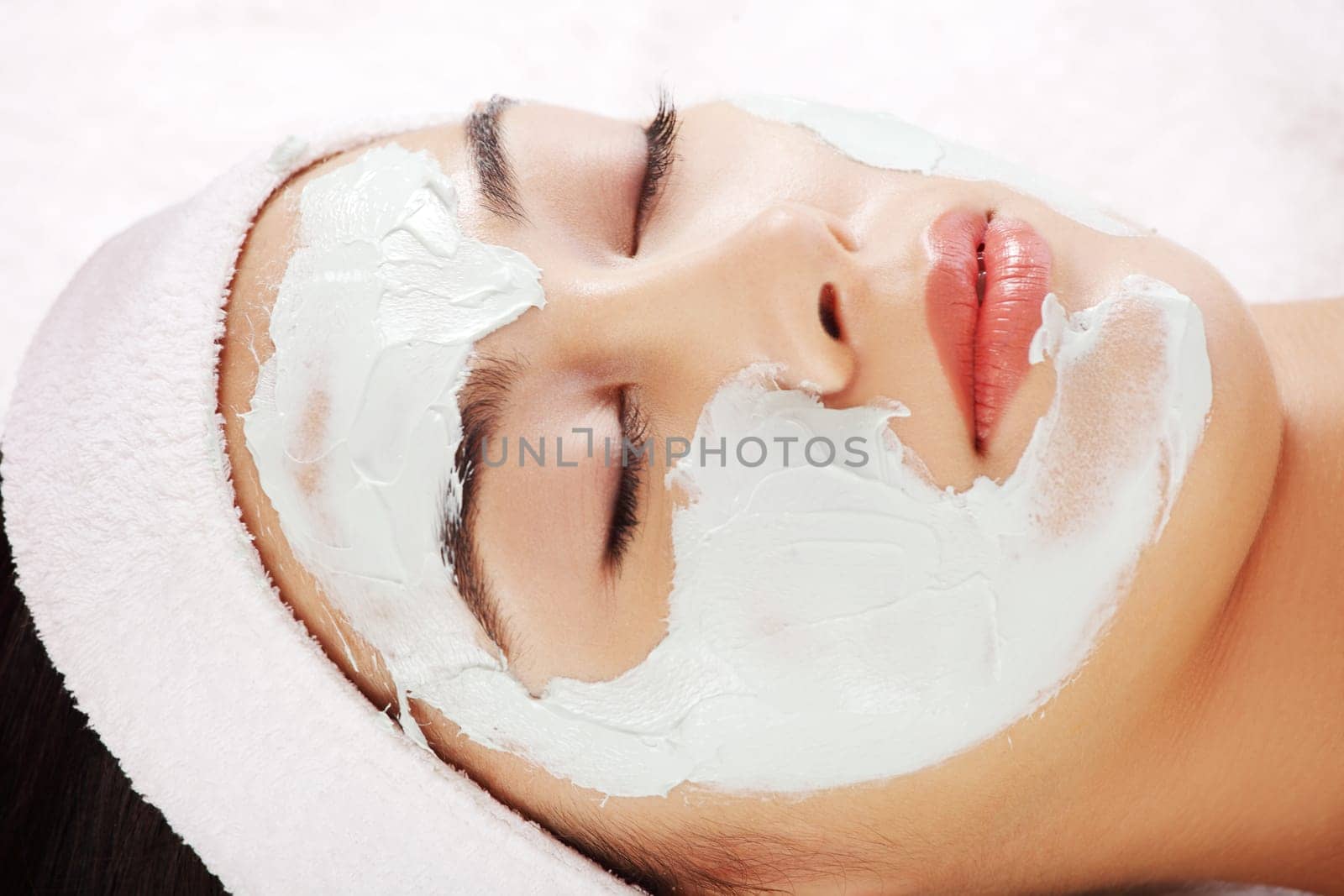 Beauty treatment in spa salon. Woman with facial clay mask.