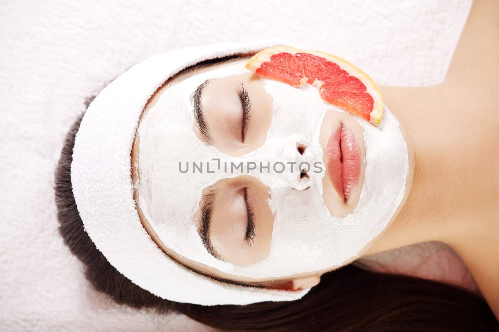 Attractive young woman with fruit mask on a face at spa saloon