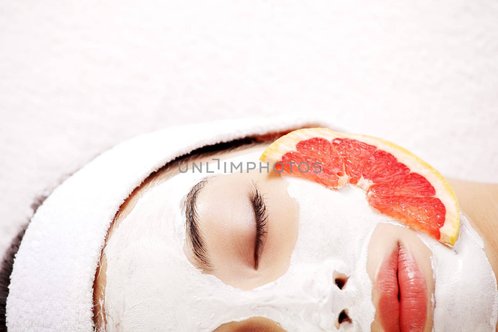 Attractive young woman with fruit mask on a face at spa saloon
