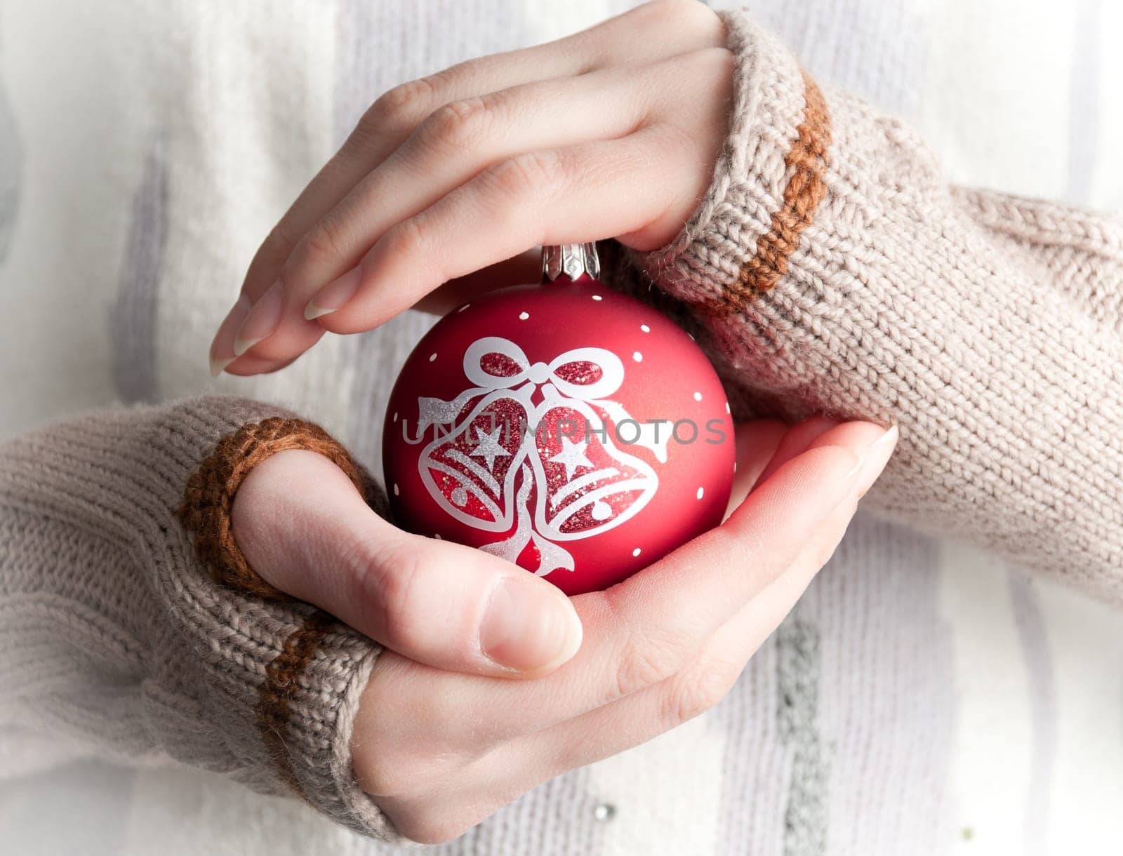 young woman wearing winter clothes holding red christmas ball toy in her hands