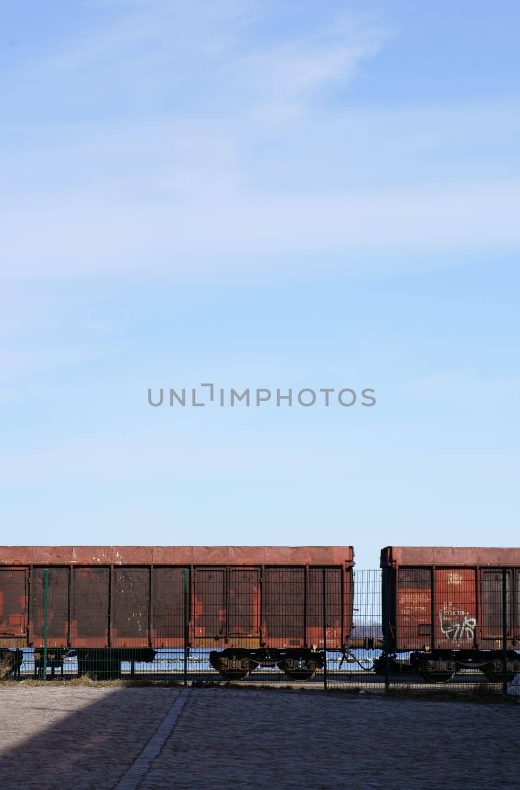 Die Seitenansicht von Eisenbahnwaggons hinter einem Zaun.