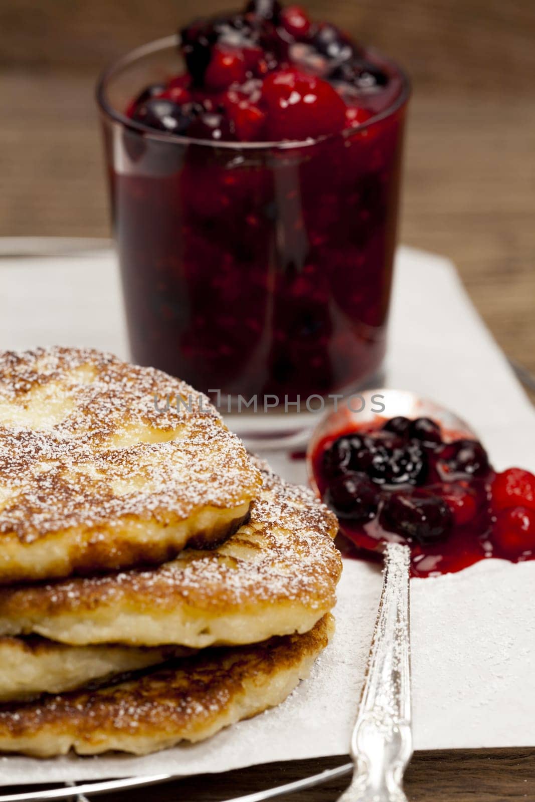 Partial view of rice pudding pancakes with homemade berry groats on a silver spoon