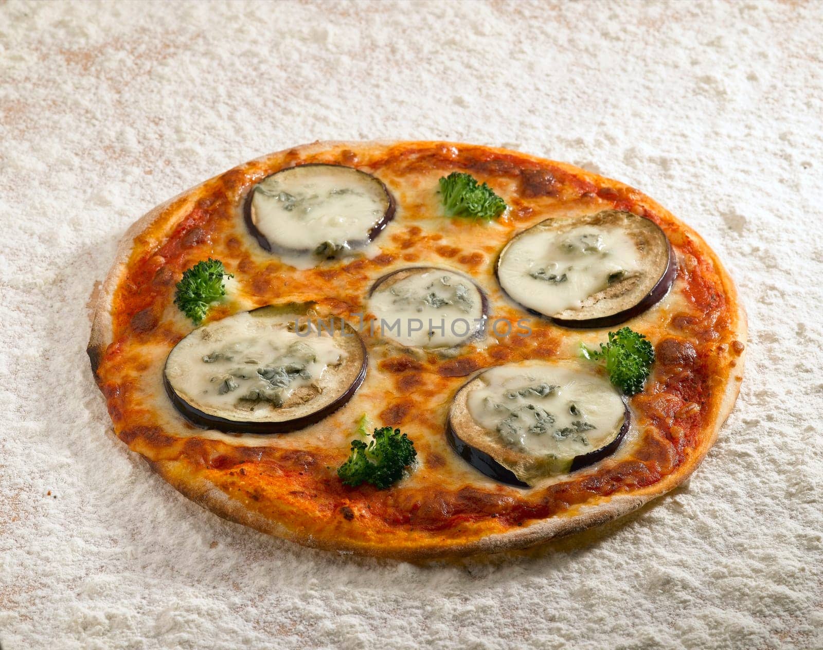 A tasty pizza eggplant on a bed of flour.