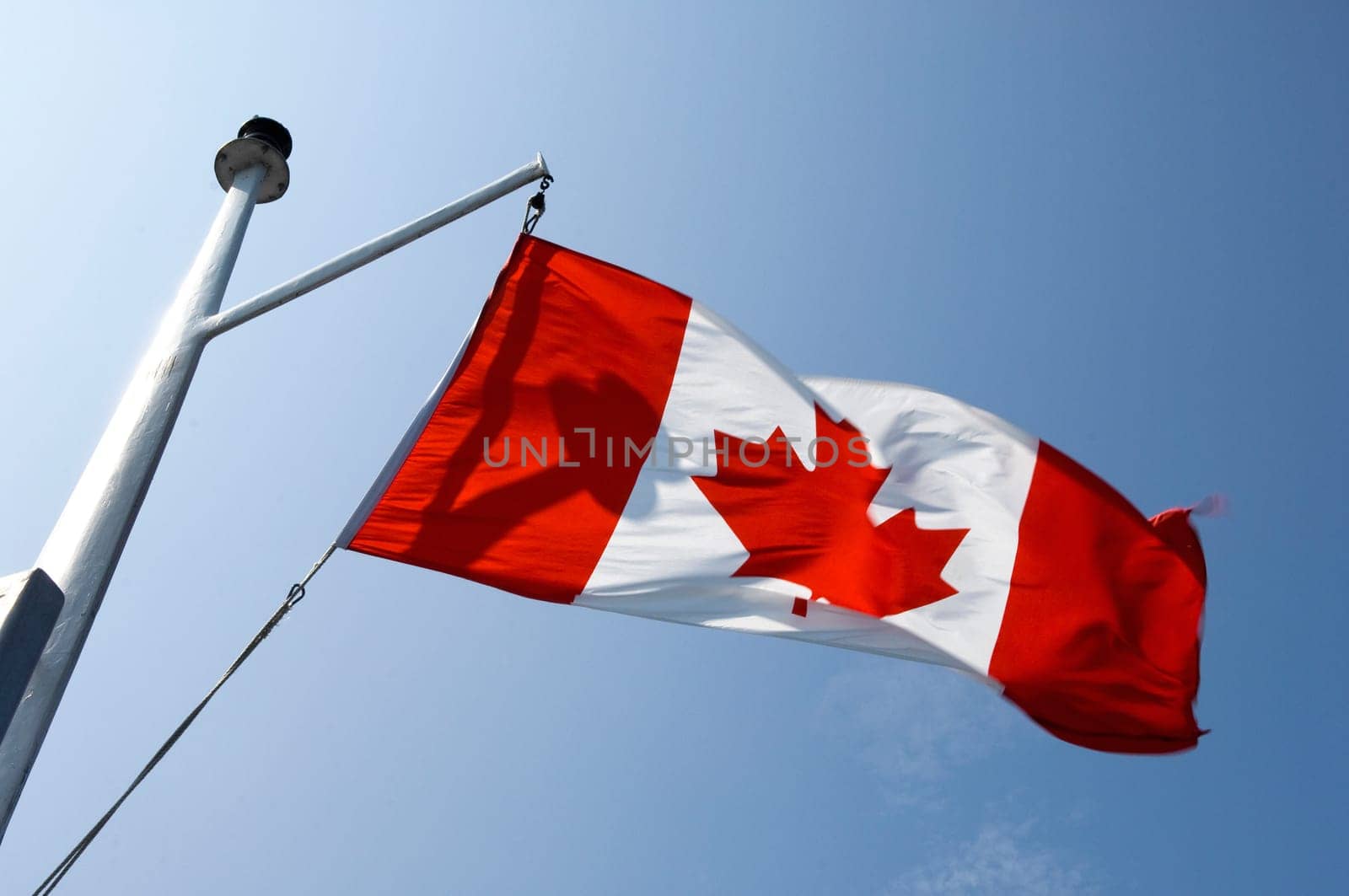 Canadian flag waving in the wind. On a ship mast