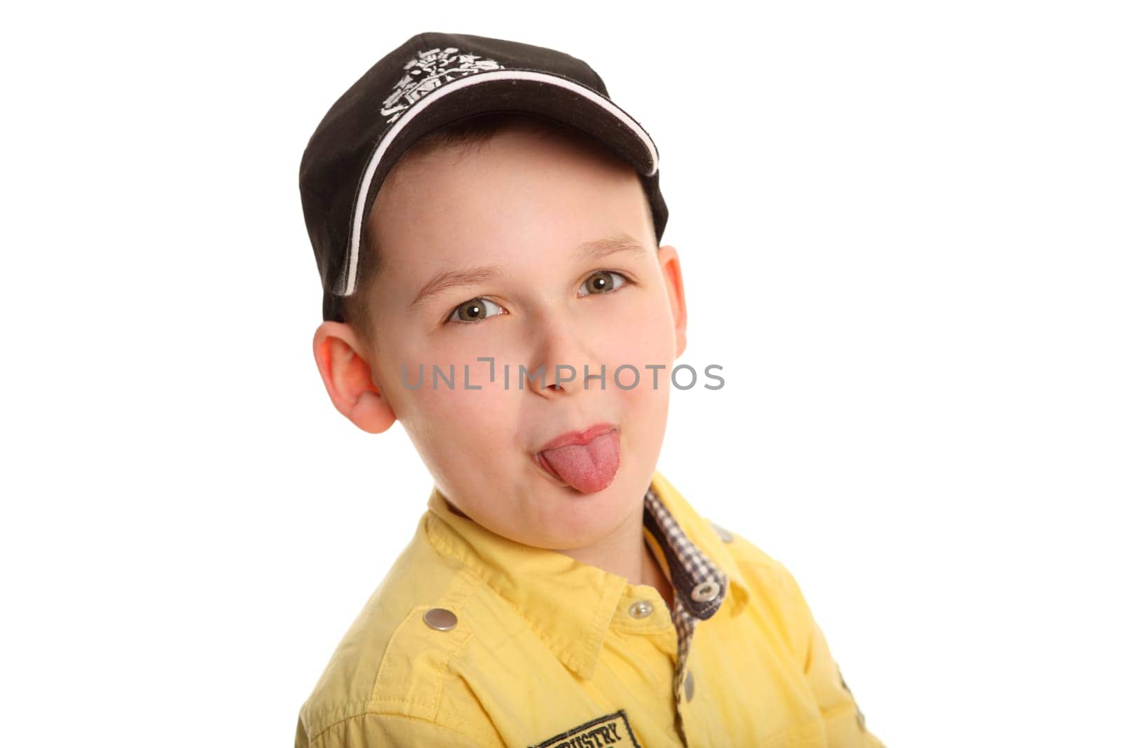 Portrait photo of a boy wearing a baseball cap and looking into the camera with his tongue outstretched.