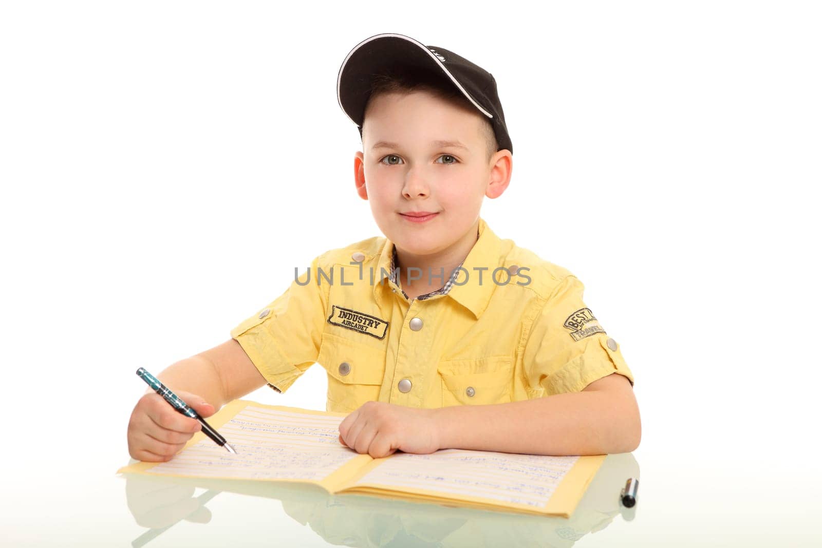 The little boy sits in front of a notebook and looks friendly,smiling into the camera