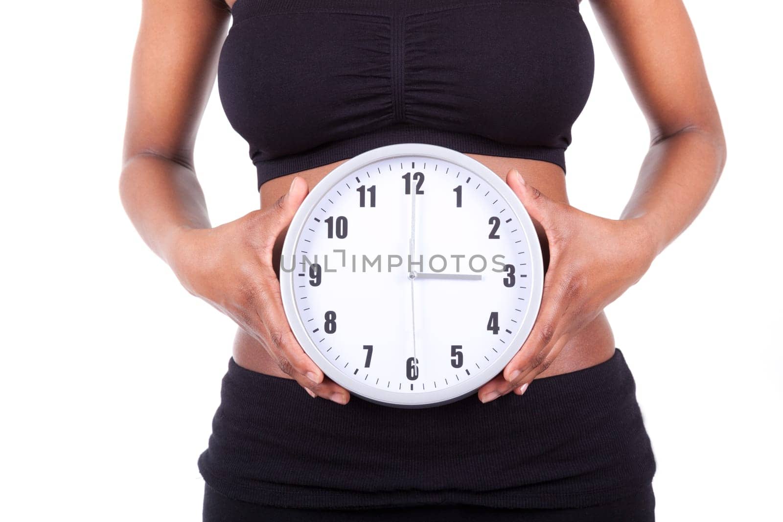 Young black african american woman holding a clock in front of her belly, isolated on white background - African people
