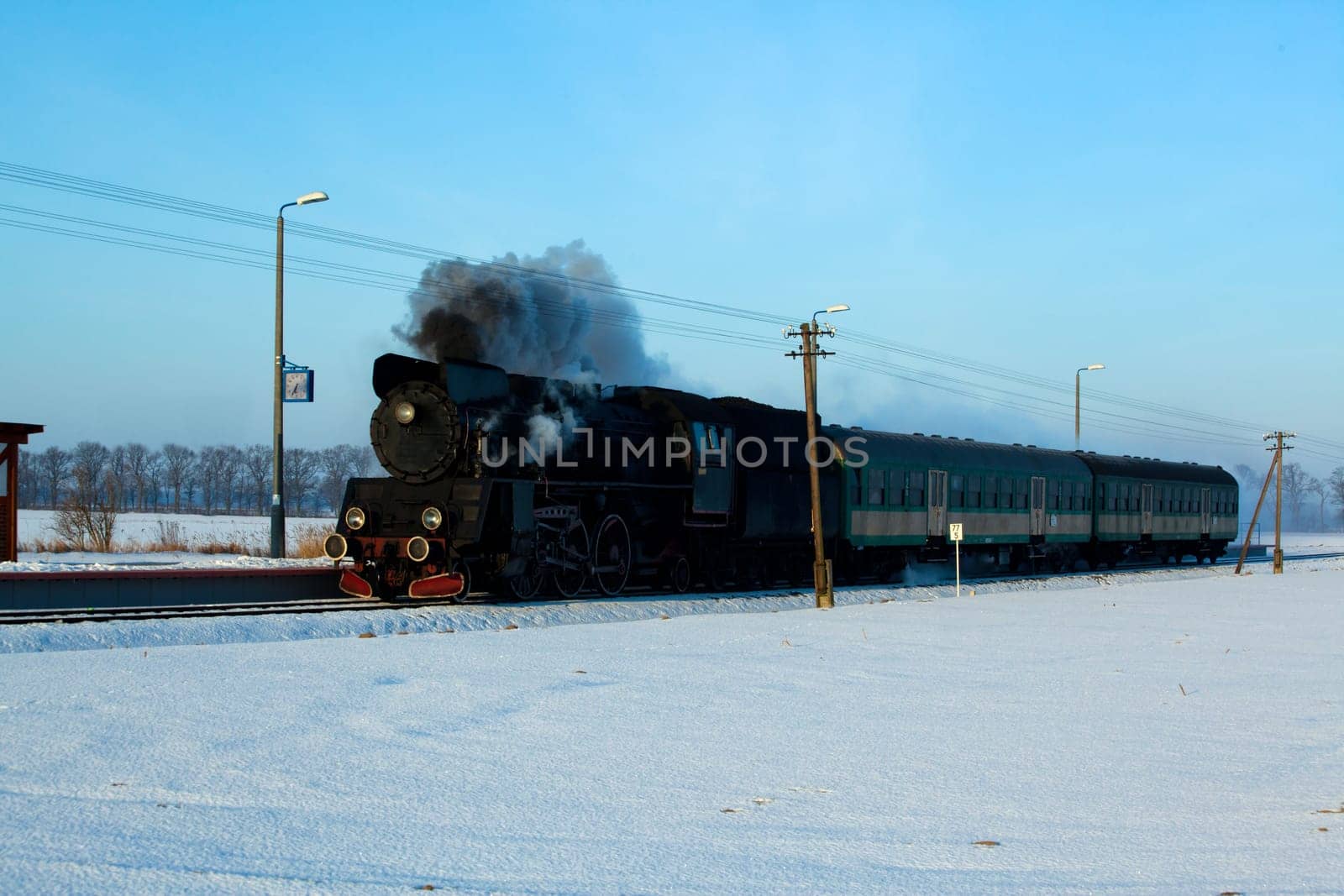 Vintage steam train puffing through countryside during wintertime