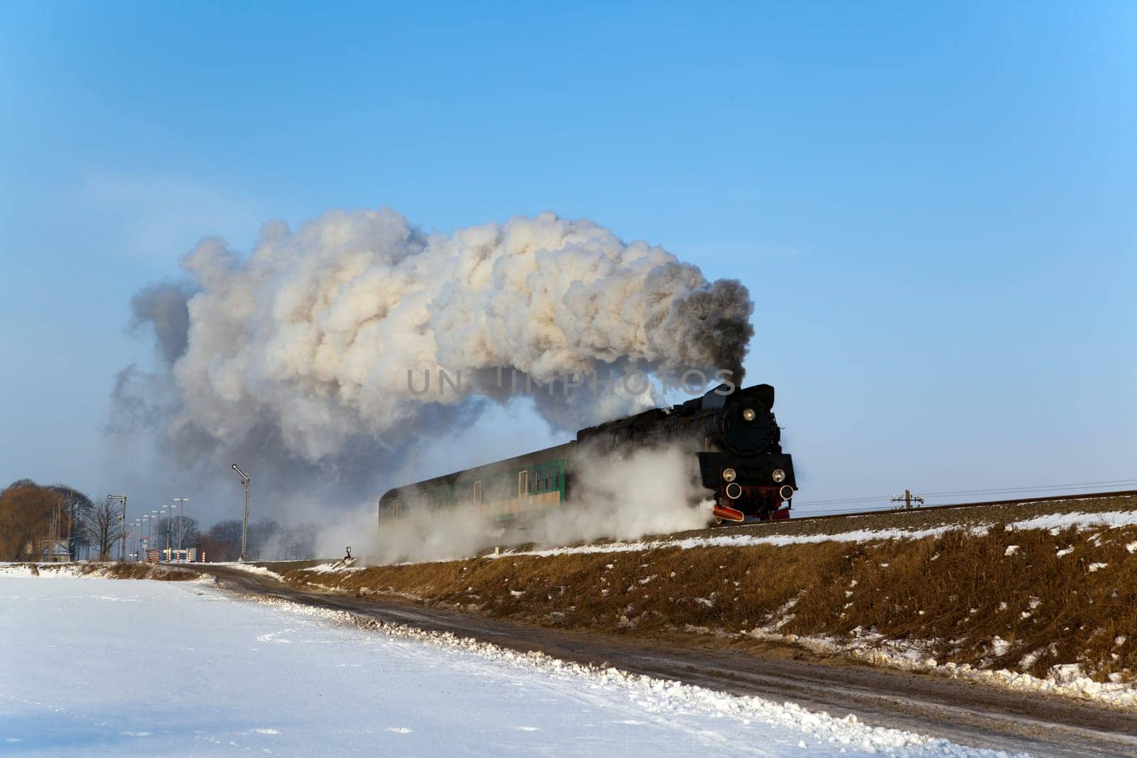 Vintage steam train puffing through countryside during wintertime