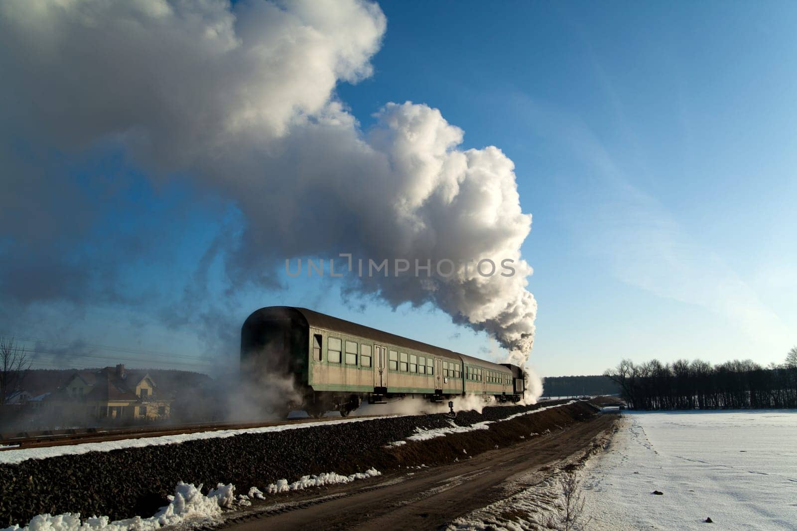 Vintage steam train puffing through countryside during wintertime
