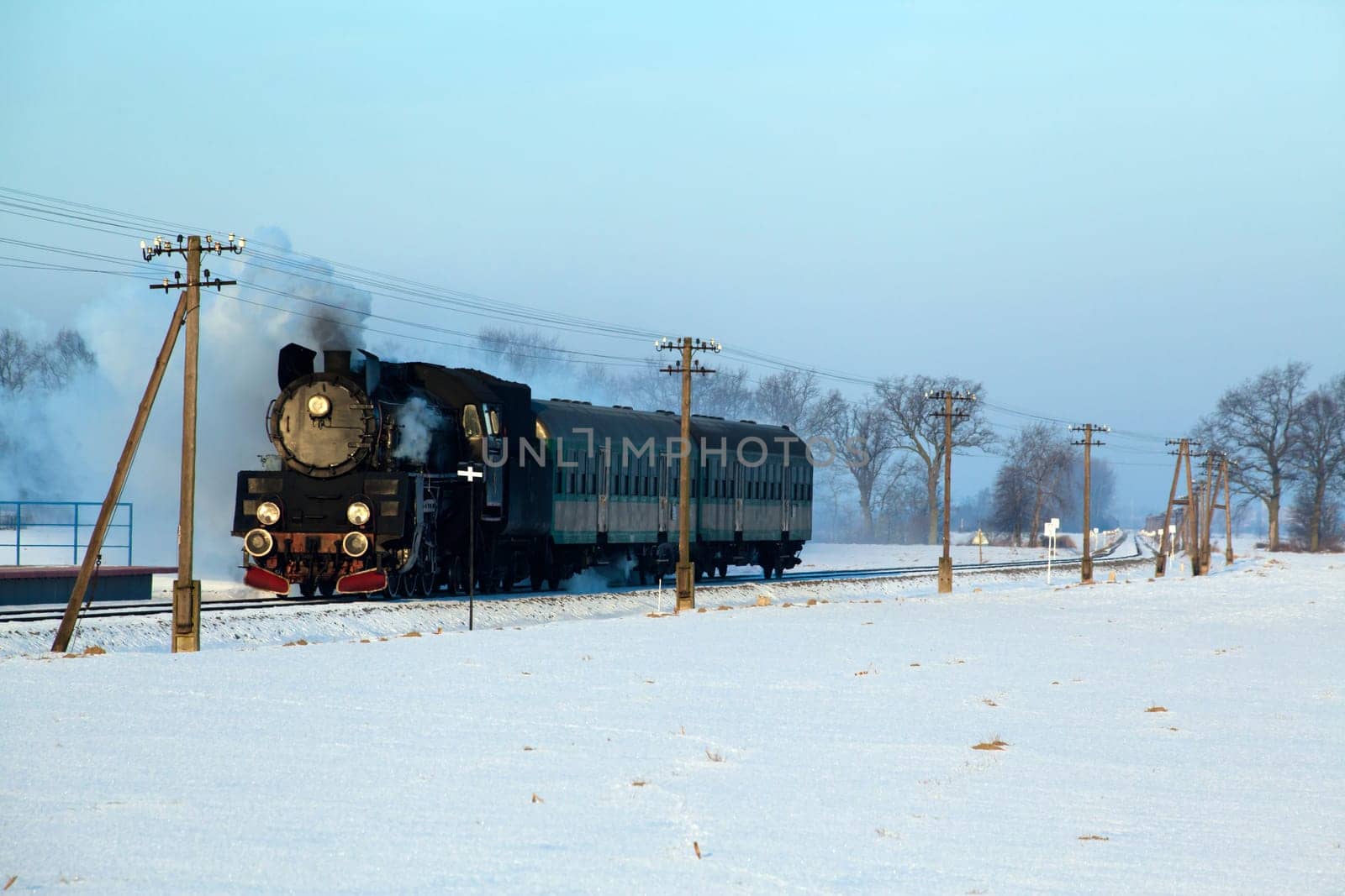 Vintage steam train puffing through countryside during wintertime