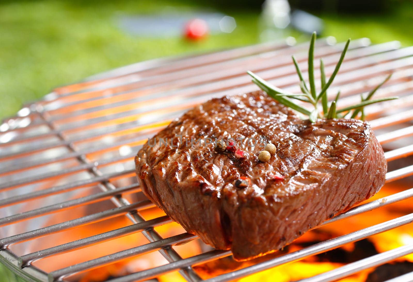 A thick strip steak being grilled outdoors