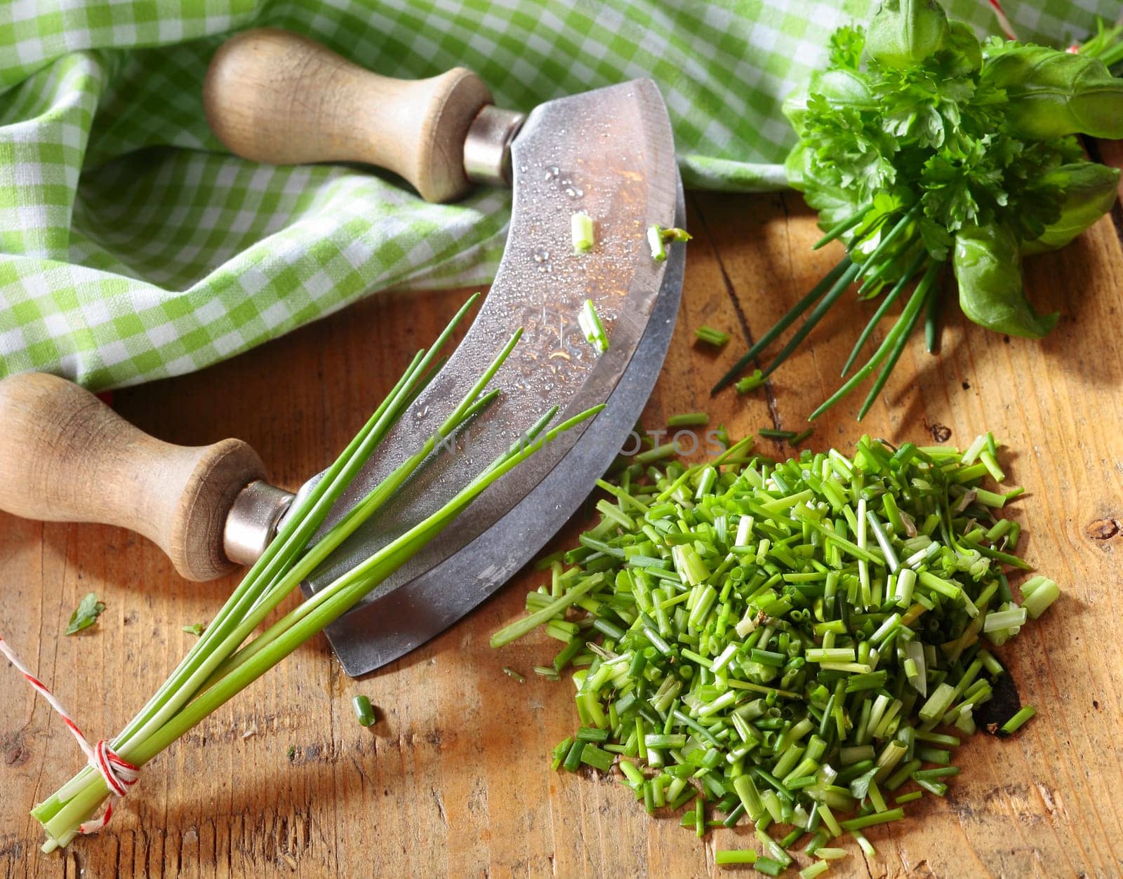 High angle view of a curved kitchen rocker blade used for chopping a pile fresh chives for use as an ingredient in cooking and salads