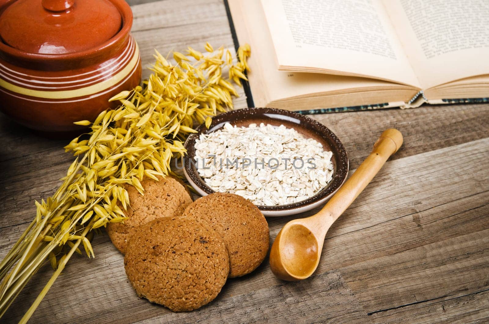Oatmeal cookies, open book of recipes and cooking utensils
