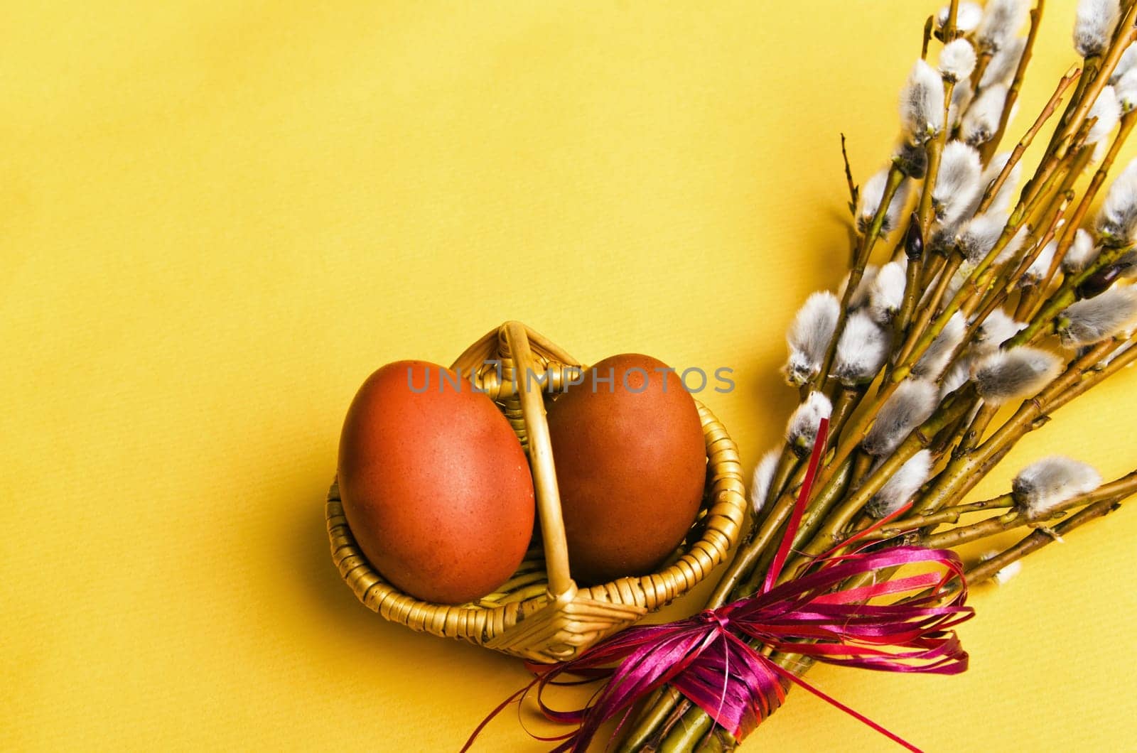 bunch of willow branches and two Easter eggs in basket