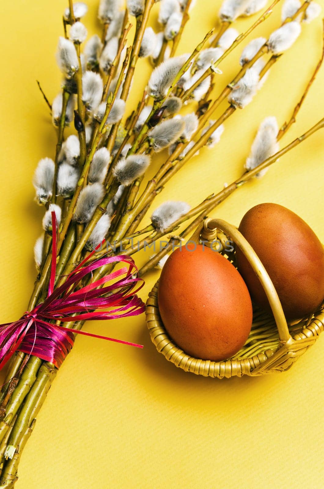 bunch of willow branches and two Easter eggs in basket