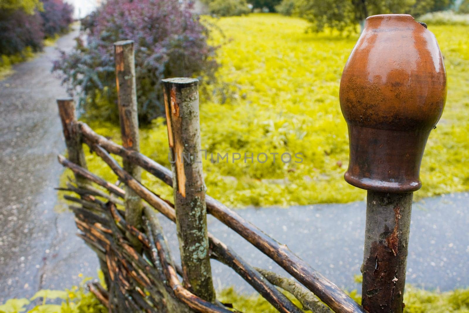 pot on wooden farm fence with grass and tree in background