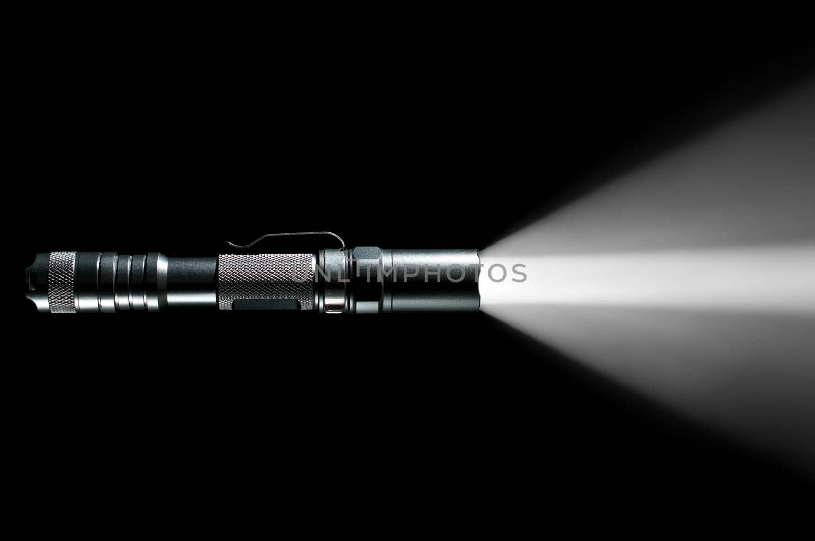 tactical police and military flashlight on black background with visible beam of light