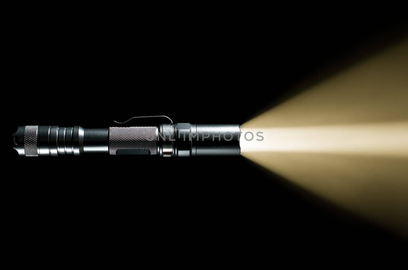 tactical police and military flashlight on black background with visible beam of light