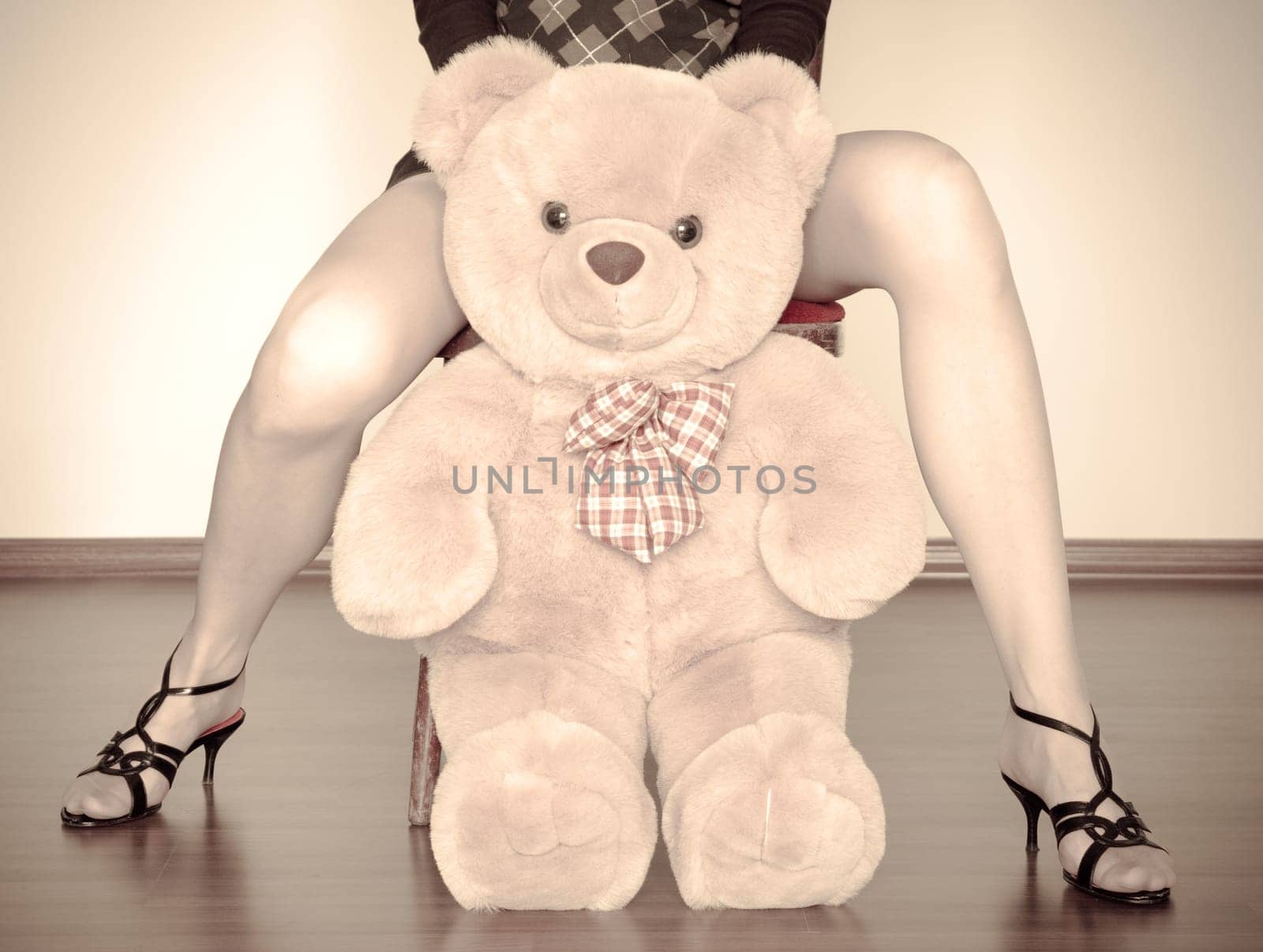 sepia photo of the toy bear between girl legs