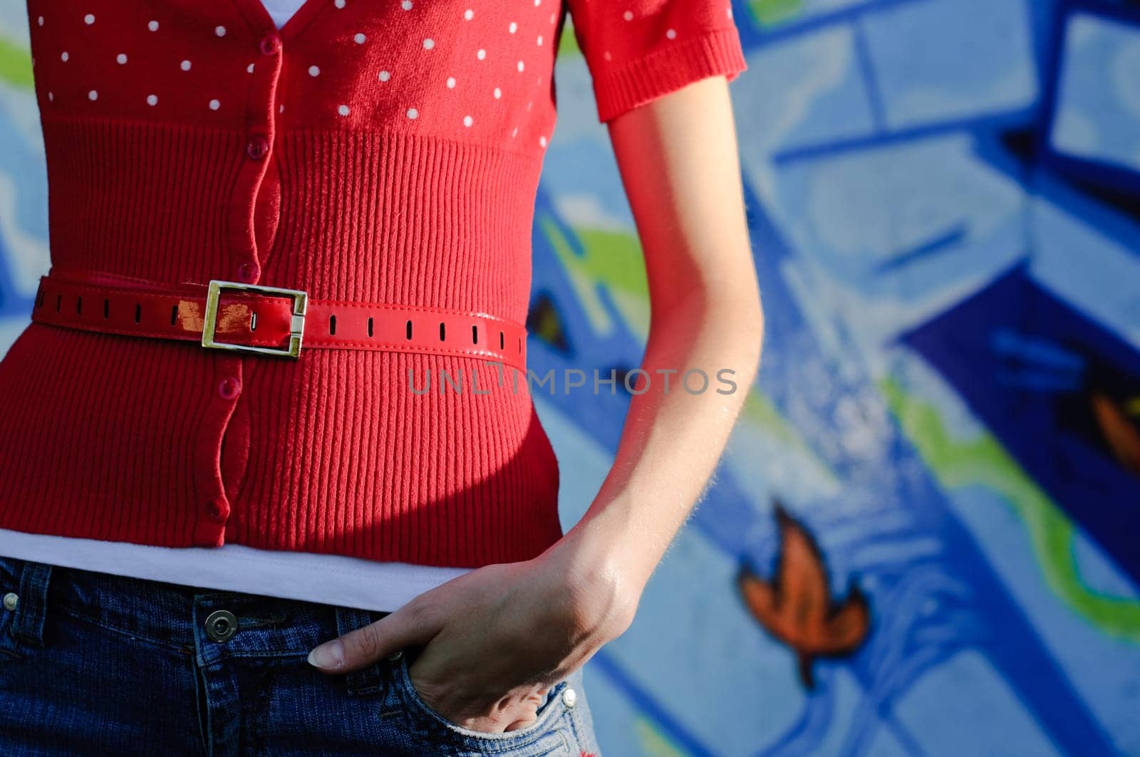 girl standing in front of the wall painted with graffiti