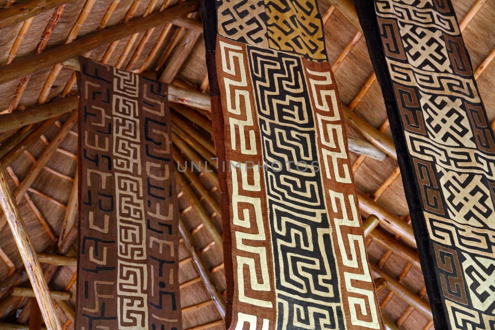 African themed fabric banners hanging from a thatch hut roof.