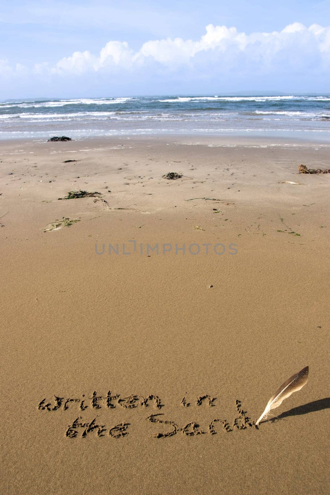 a feather used as a quill pen to write written in the sand on an irish coastal beach