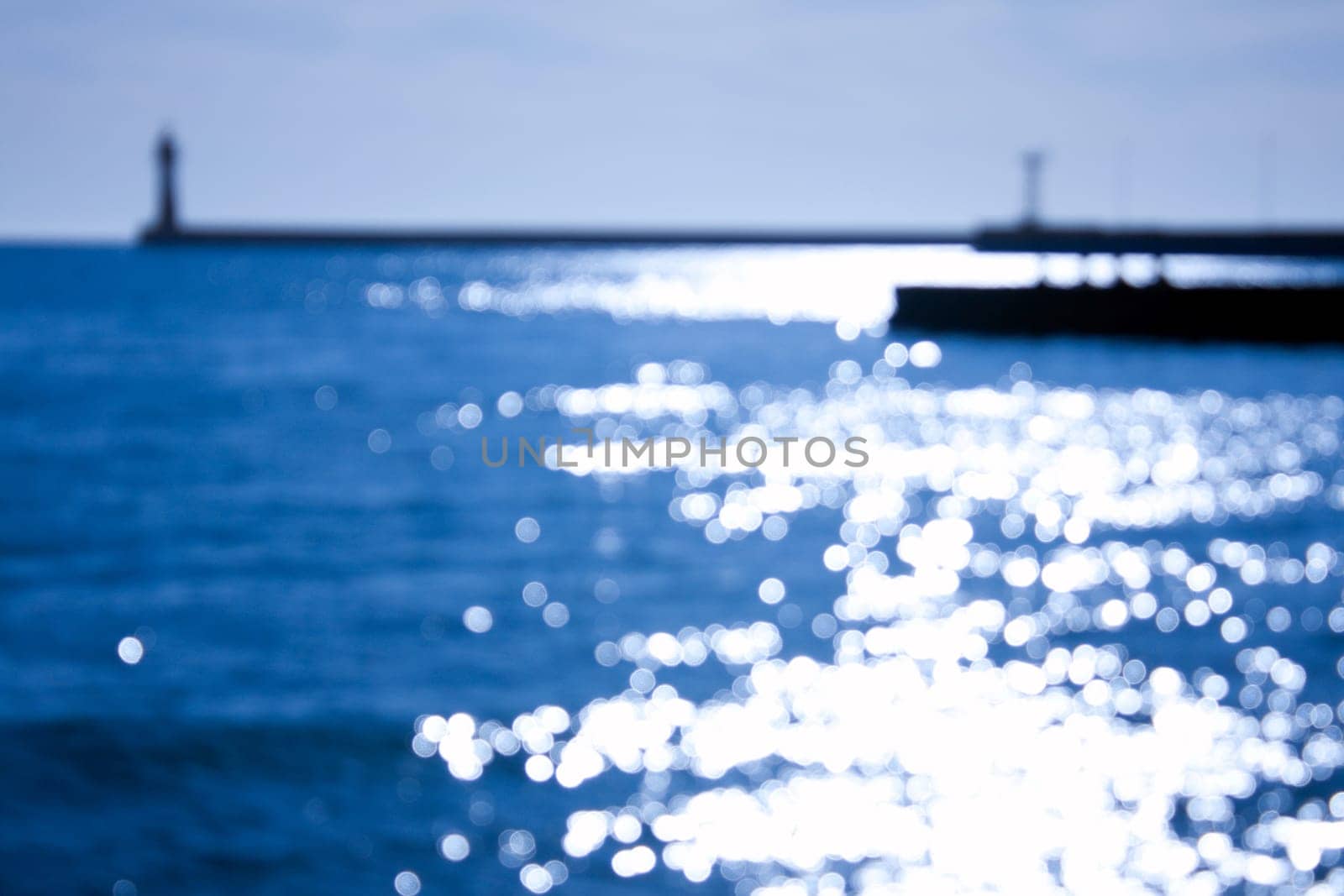 blured sea lighthouse with sunlight reflecting from water surface