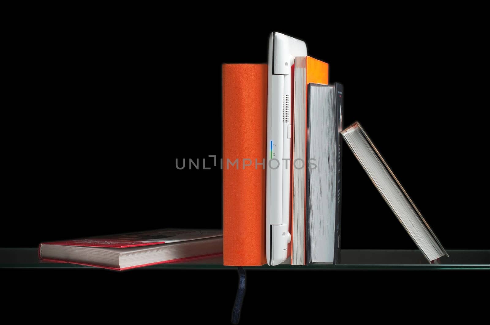 white laptop computer between books on the glass shelf