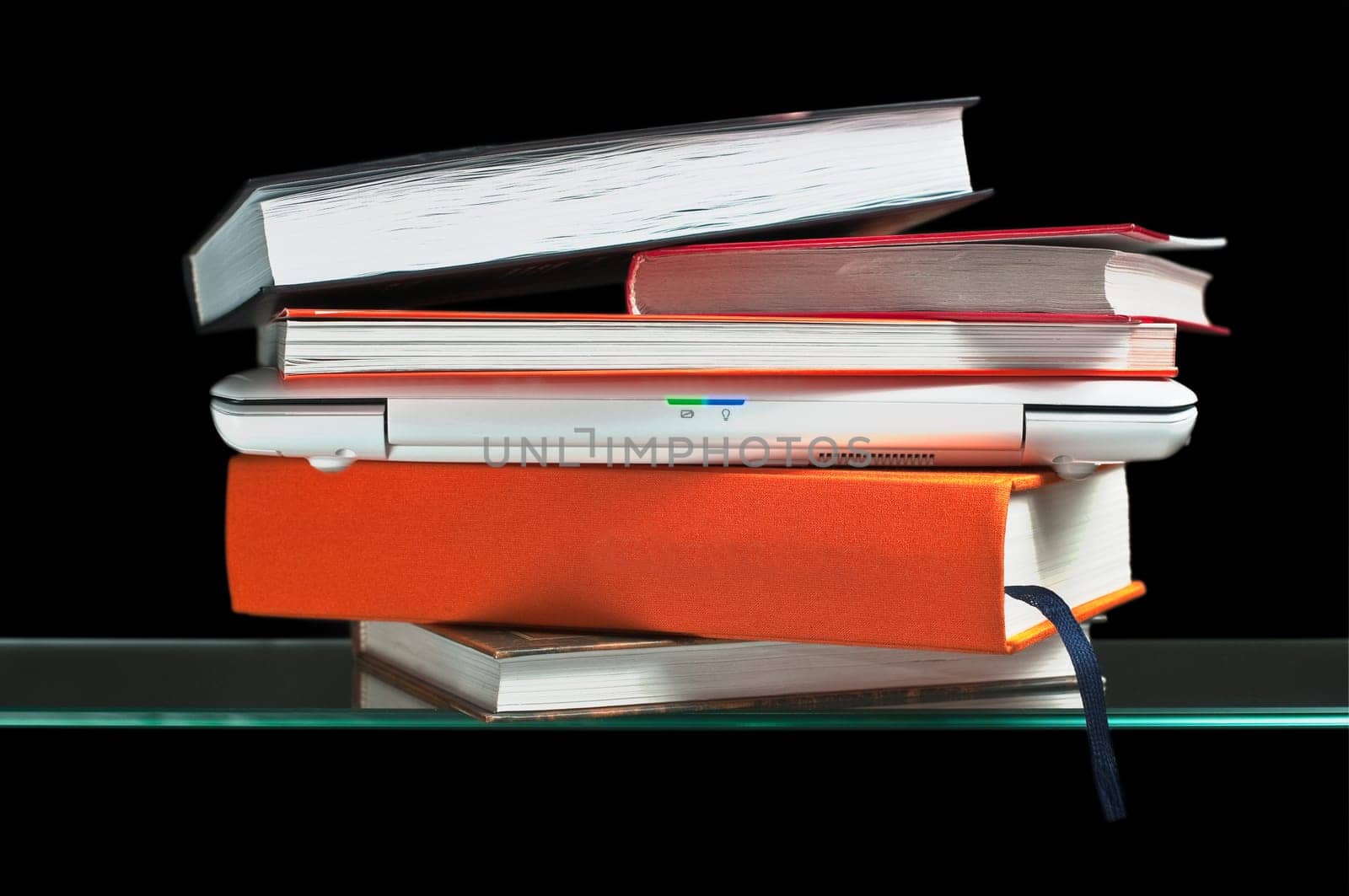 white laptop computer between books on the glass shelf