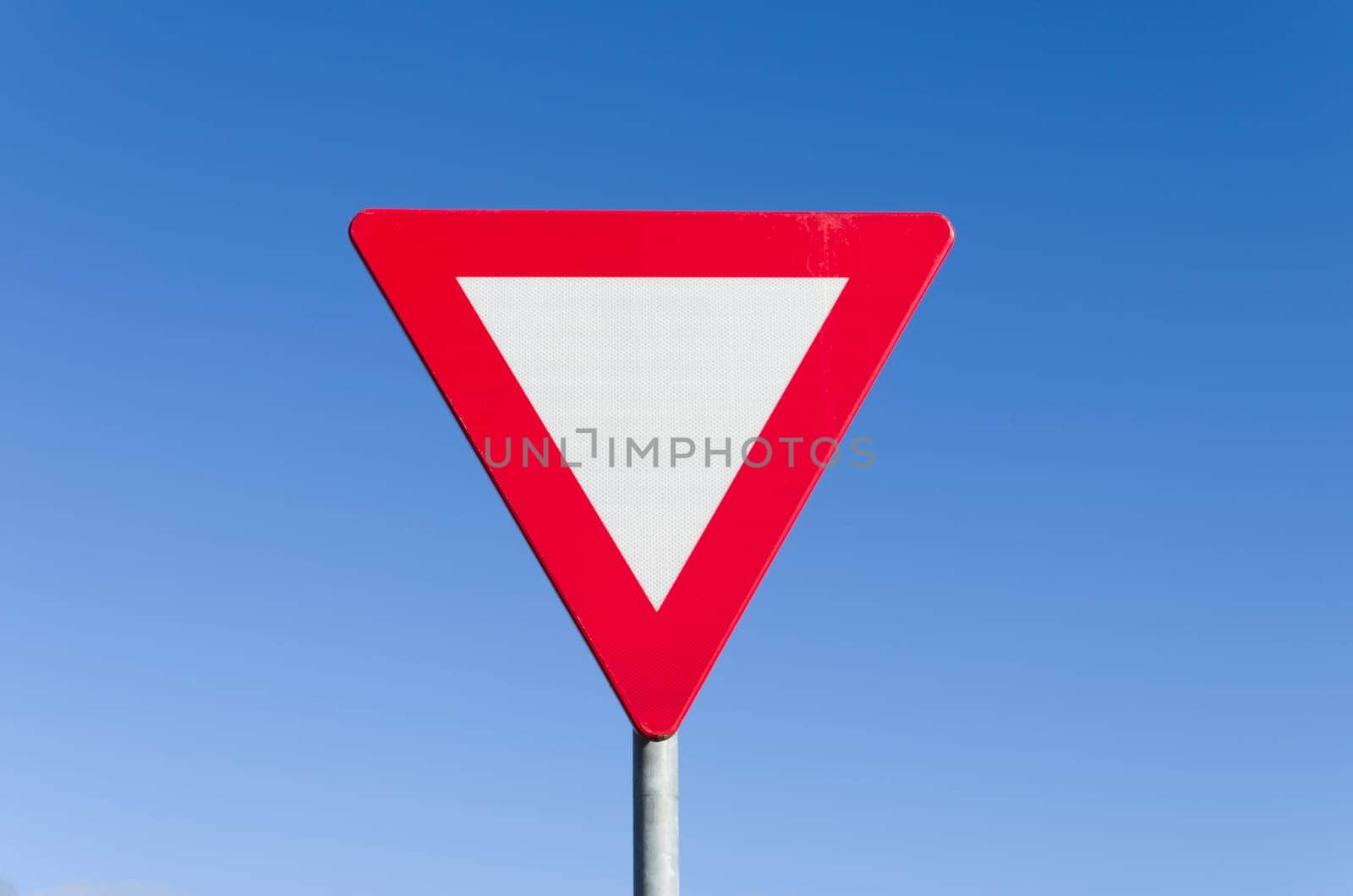 give way traffic sign against a clear blue sky