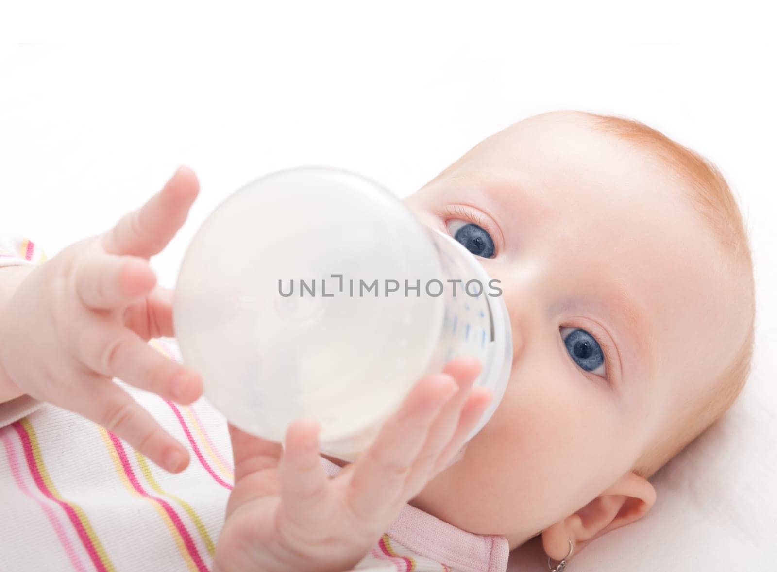 Baby Girl Drinking Milk from Bottle on White Background - Shallow Depth of Field