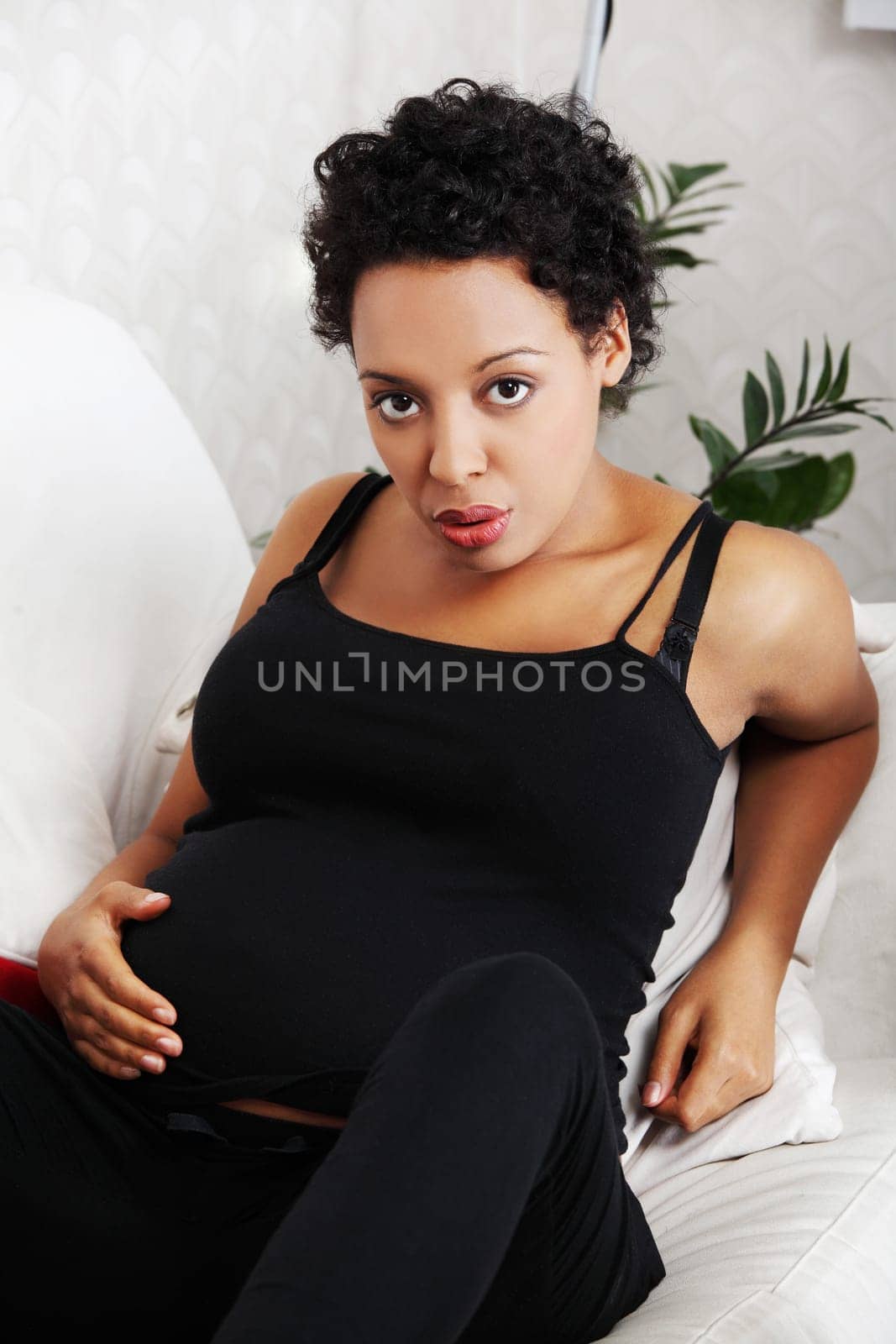 Young pregnant woman sitting on sofa