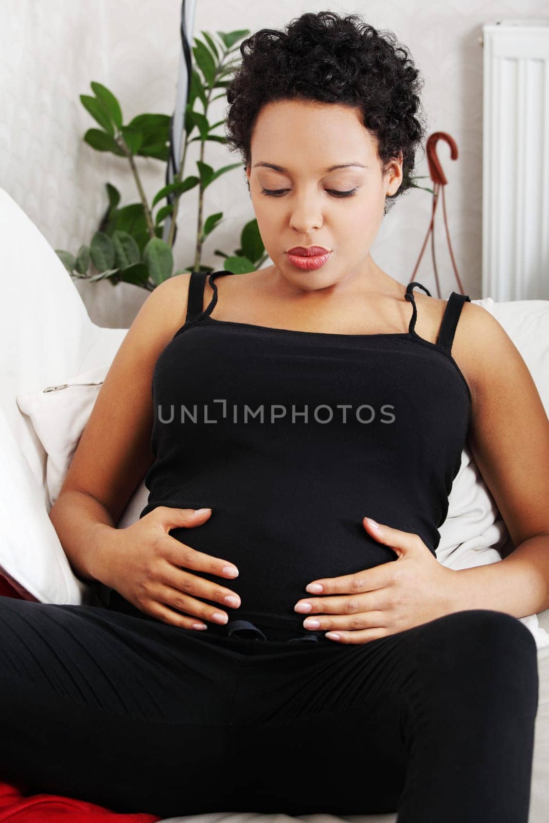 Young pregnant woman sitting on sofa