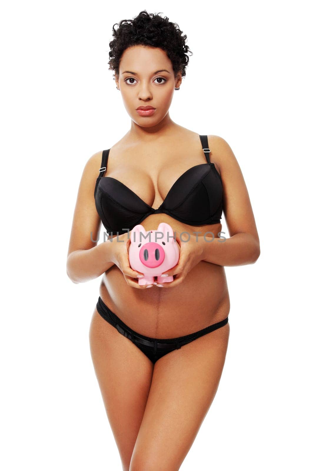 Young beautiful pregnant woman holding a pink piggybank in front of her belly, over a white background.